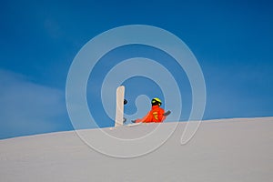Snowboarder freerider with white snowboard sitting on the top of the ski slope