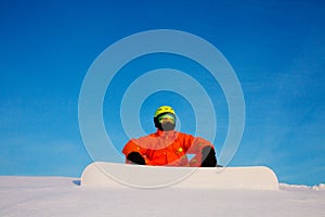 Snowboarder freerider with white snowboard sitting on the top of the ski slope