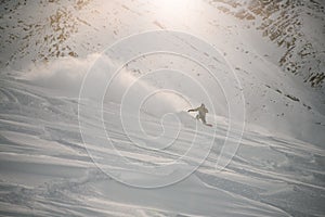 Snowboarder in full equipment rides on a snowboard in mountains