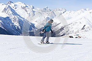 Snowboarder girl on the background of the mountains.