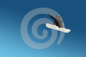 Snowboarder girl does a trick in jumping with a grab against the blue sky. Blue gradient background isolated athlete in