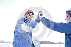 Snowboarder high fives girlfriend on the mountainside