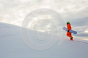 Snowboarder climbing on the top of ski slope