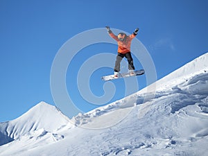 Snowboarder jump in the mountains against the blue sky