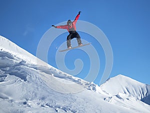 Snowboarder jump in the mountains against the blue sky