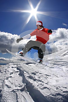 Snowboarder jumping against blue sky