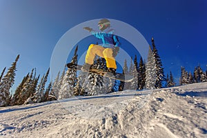 Snowboarder jumping against blue sky