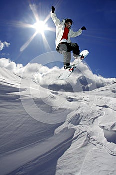 Snowboarder jumping against sun