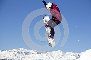 Snowboarder jumping through air with blue sky background