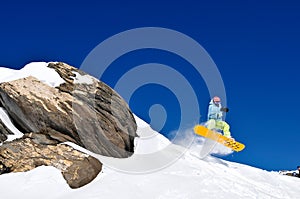 Snowboarder jumping of cliff at fresh snow