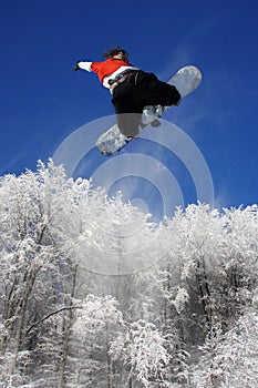 Snowboarder is jumping over the forest