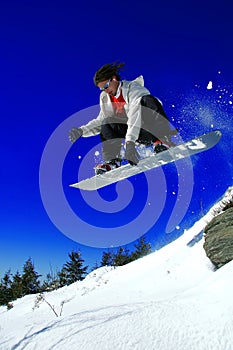 Snowboarder jumping over the rock