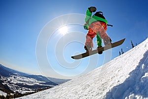 Snowboarder jumping from the springboard against the sky