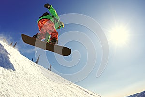 Snowboarder jumping from the springboard against the sky