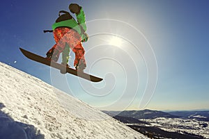 Snowboarder jumping from the springboard against the sky