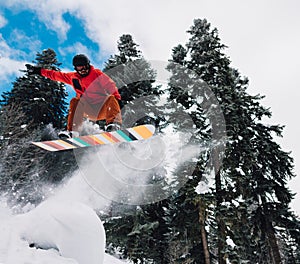 Snowboarder is jumping very hight and freeriding from the hill in the mountain forest