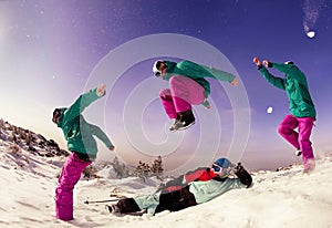 Snowboarder jumps over lying skier on background of mountains