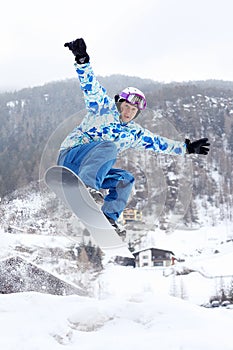 Snowboarder jumps on snowboard