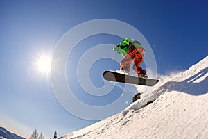 The snowboarder jumps from the springboard against the blue sky