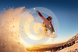 Snowboarder jumps sunset with snow dust