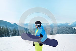 Snowboarder Of Man At Ski Resort On The Background Blue Sky,  Hold Snowboard. Wearing Ski Glasses.