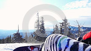 Snowboarder man in suit of kigurumi of zebra relaxing in the mountains in slowmotion on the sun background with lens