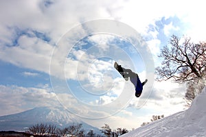 Snowboarder mid backflip at hanazono backcountry jump