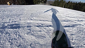 Snowboarder moves on a snowboard, his shadow moves before him on the snow synchronously