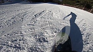 Snowboarder Moves on a Snowboard, His Shadow Moves Before Him on the Snow Synchronously