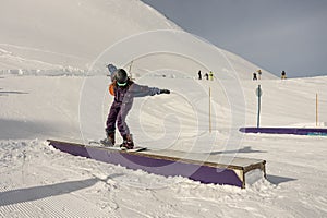 Snowboarder in the park on a box. Snow park box tricks. Winter jibbing in snwopark in France