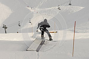 Snowboarder in the park on a box. Snow park box tricks. Winter jibbing in snwopark in France