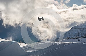 Snowboarder performing flip off a large jump in the mountains