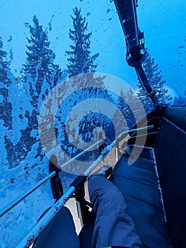 Snowboarder point of view sitting at chair lift with wind shield