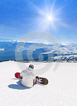 Snowboarder relaxing against mountains in sun rays, winter sports holidays travel at ski health resort concept