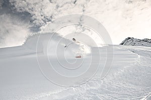 Snowboarder rides through the snow on mountain side