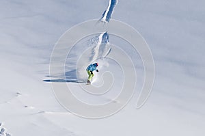 Snowboarder riding down on fresh backcountry snow