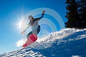 Snowboarder Riding Red Snowboard in Mountains at Sunny Day. Snowboarding and Winter Sports