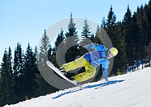 Snowboarder riding snowboard down snowy mountain slope on sunny winter day. Extreme sport concept.