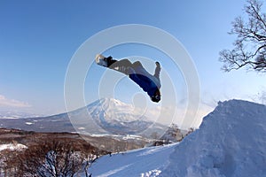 Snowboarder sending it off backcountry jump photo