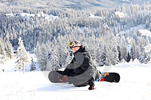 Snowboarder sitting on a mountain slope