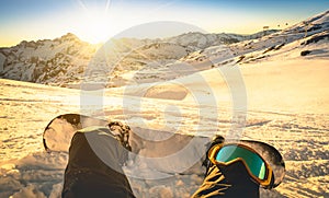 Snowboarder sitting on relax moment at sunset in ski resort