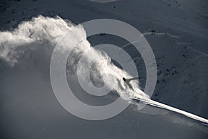 Snowboarder slides on a snowboard through snow cloud