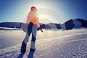 Snowboarder with snowboard face the snowobard piste in winter mountains