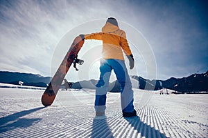 snowboarder with snowboard looking at the snowobard piste on winter mountains