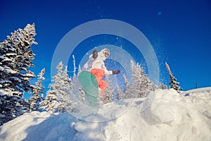 Snowboarder on snowboard rides jumping on fresh snow in forest, dust explosion. Freeride in Alps Ski Resort