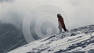 Snowboarder with snowboard walking on snowy mountain to peak. Snowboarder rising up on snowy mountain peak for riding on