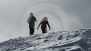 Snowboarder with snowboard walking on snowy mountain to peak. Snowboarder rising up on snowy mountain peak for riding on