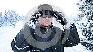 Snowboarder standing on a ski slope in winter and keeps his hands a ski mask