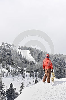 Snowboarder on the top of a mountain slope in a winter day