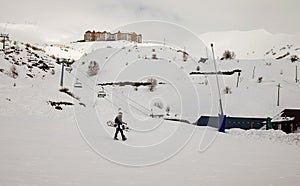 Snowboarder walking with a snowboard in the winter ski resort.